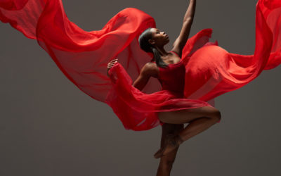 Contemporary female ballet dancer, Sadiya Ramos, with red flowy material, shot in the studio. Photograph taken in New York City by Rachel Neville.